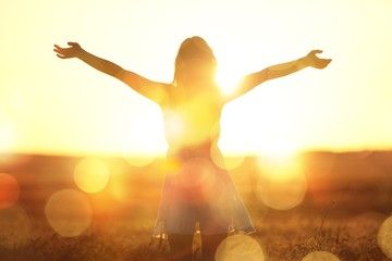 Person auf Feld mit Sonne im Hintergrund